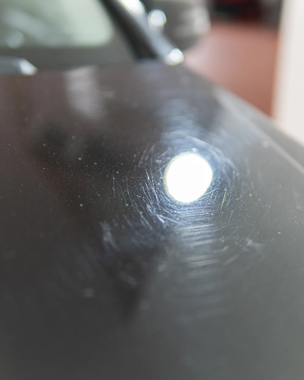 Motorhaube mit Kratzern und Hologrammen vor der Fahrzeugaufbereitung