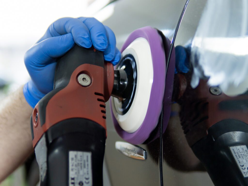 Mitarbeiter bei der Autoaufbereitung mit einer Poliermaschine